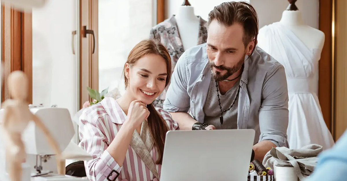 Apparel designers looking at laptop at work desk.