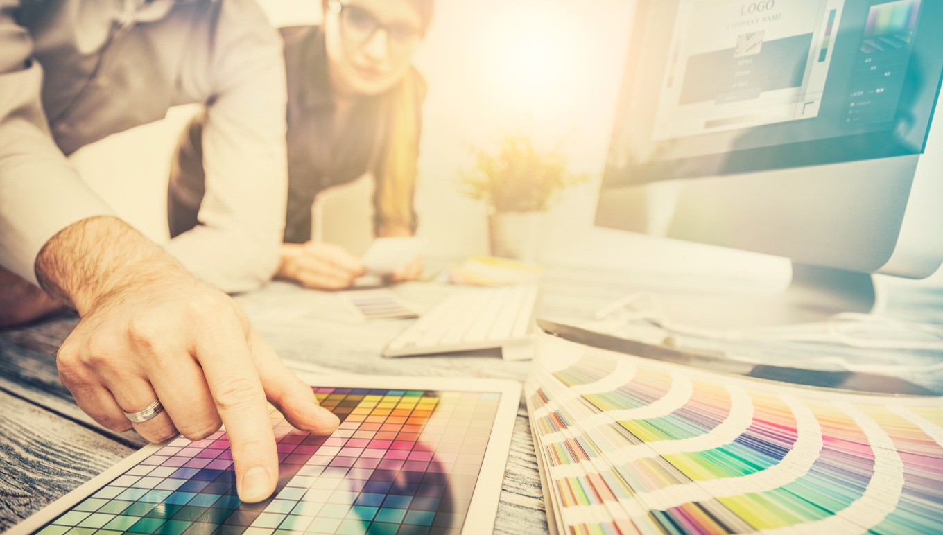 New product development professionals consult color charts while using a PLM system.
