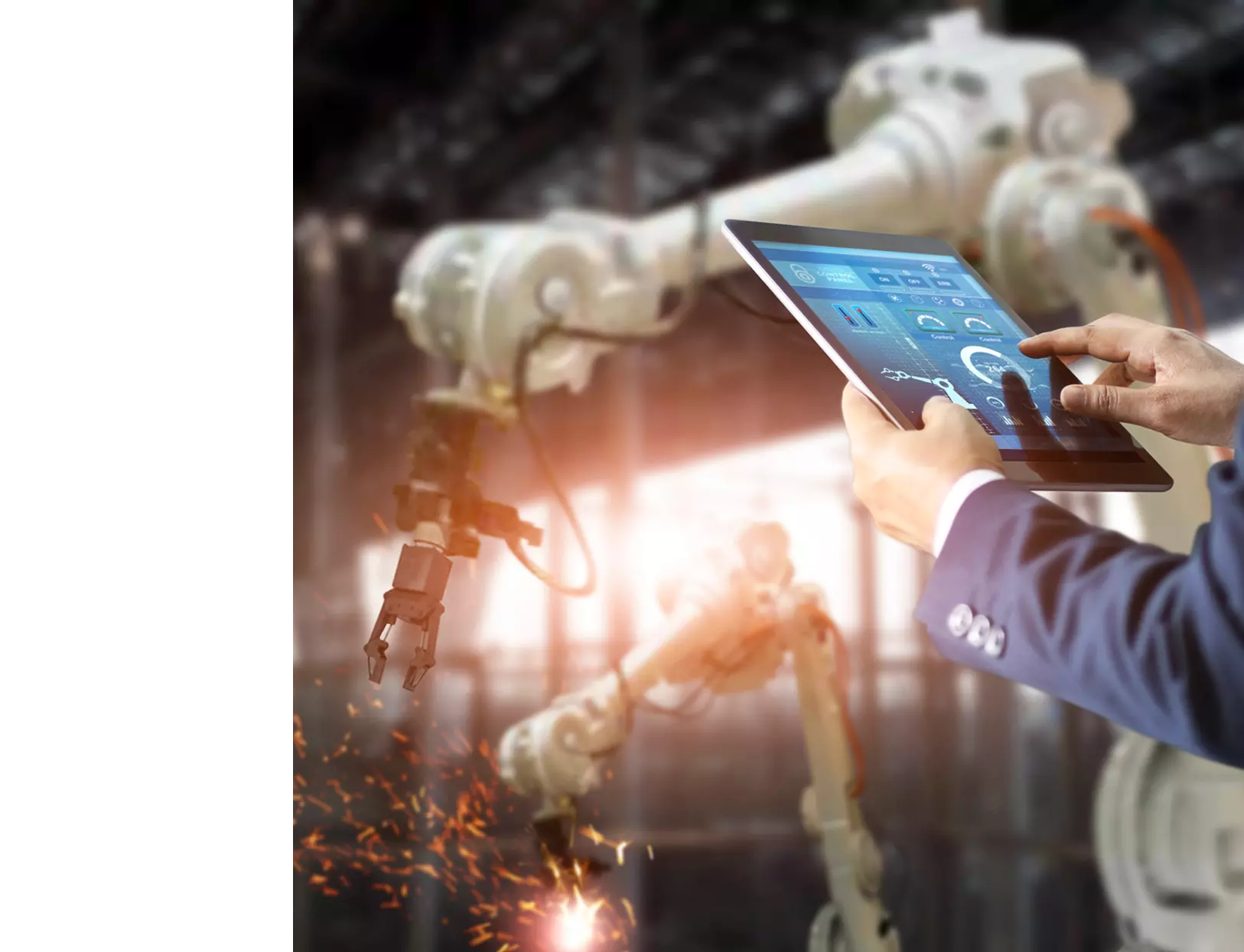 A man in a factory using his tablet to control robotic arm.