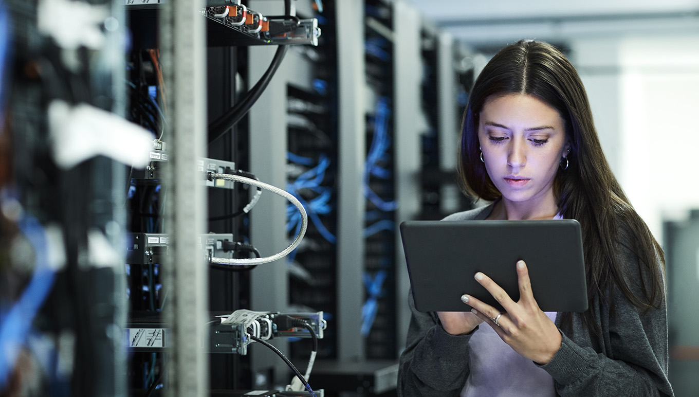Network engineer in server room reading tablet display