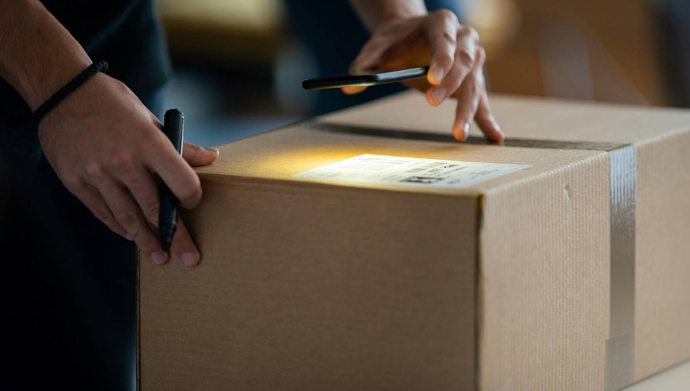 shining light on cardboard box shipping label and marker in hand