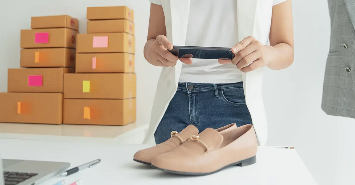 Online merchant taking photo of shoes to sell online.