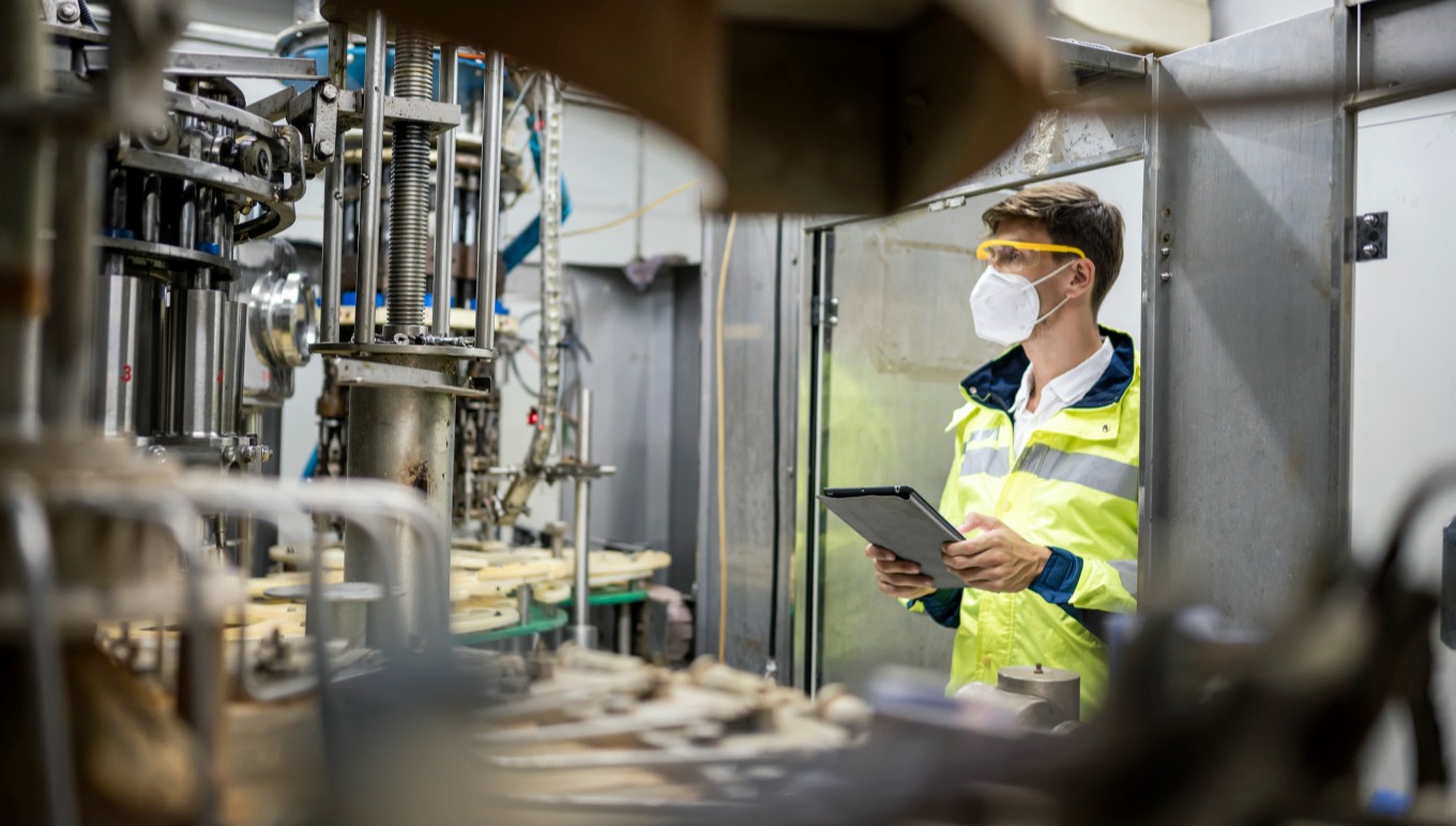 https://images.aptean.com/apteanmarketimages/5MCD4wI0VZrH7AaTVkFZas/Engineer_working_at_Fruit_juice_Bottle_Automated_conveyor_belt.jpg