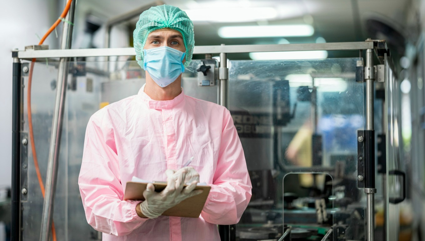 Food factory worker wearing mask holding clipboard