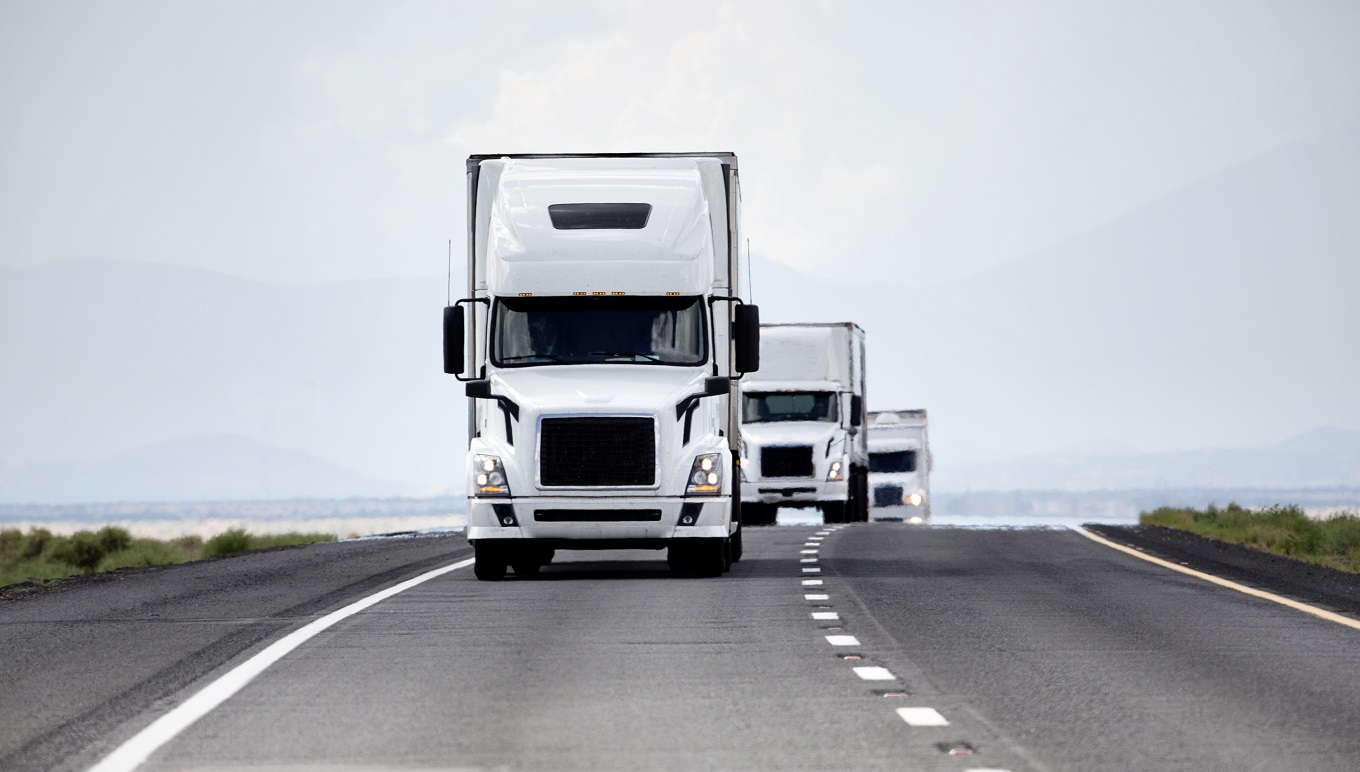 Fleet of trucks driving down a highway.