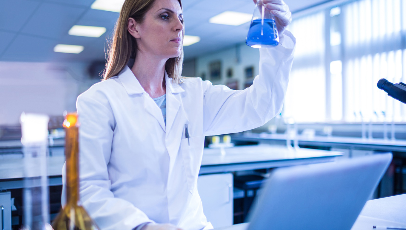 Scientist in lab looking at beaker