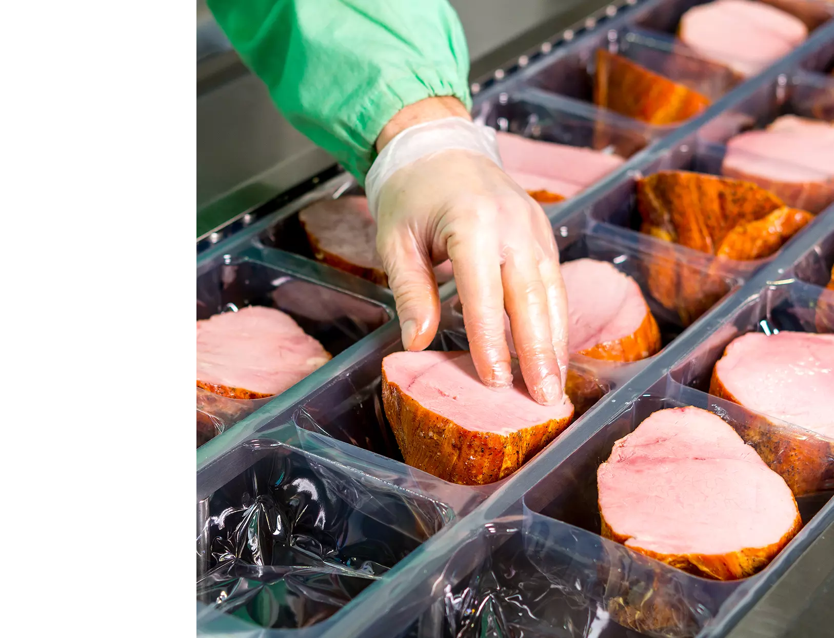 Food factory working handling meat products for packaging.